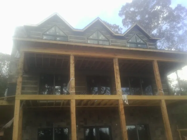 Dormers and porch framing on a large log home under construction — Roof Coating work by our crew in Sumner