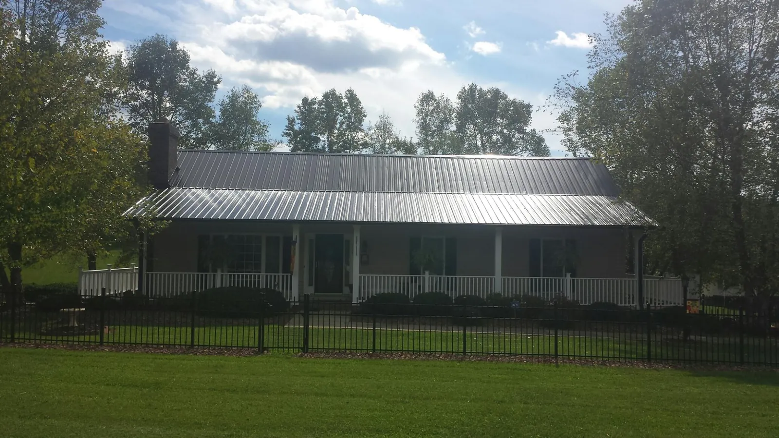Gray metal roof on a brick ranch with a full width front porch — Gutter Guard Installation work by our crew in Sumner