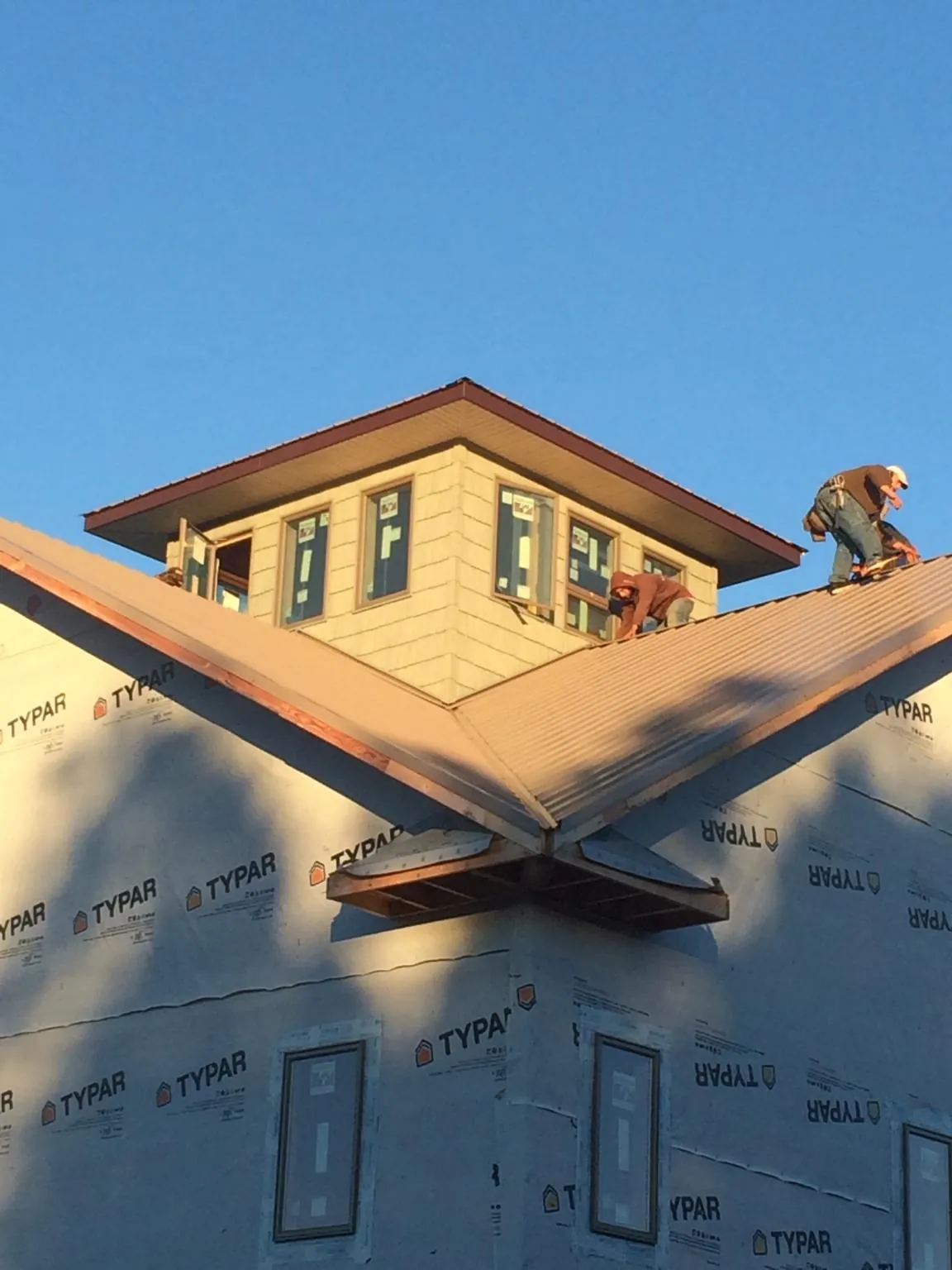 Roofers working around a rooftop cupola on a new metal roof at sunset — Roof Waterproofing in Sumner by Roofing Brothers